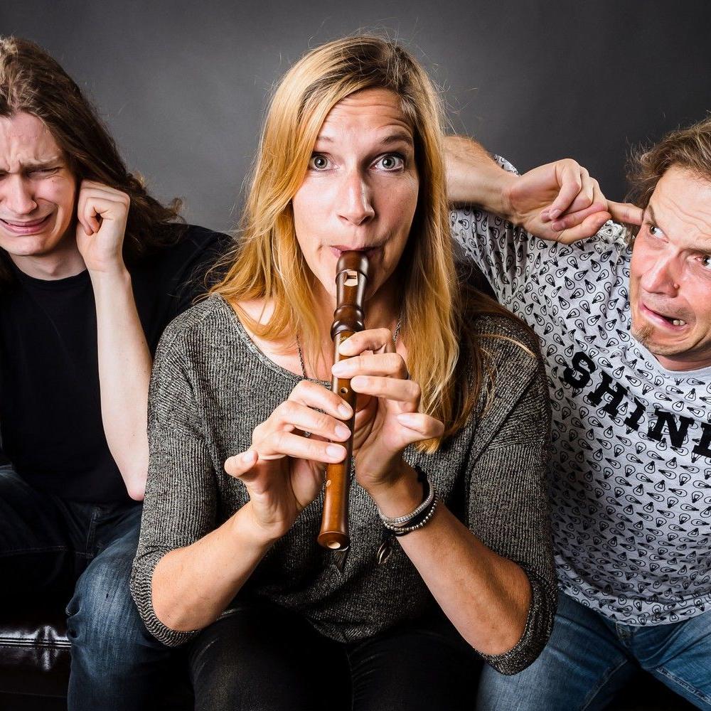 Stephanie bläst in eine Blockflöte, Anton und Dirk schauen mit entsetzten Gesichtern zu ihr, als spiele sie falsch